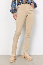 Load image into Gallery viewer, A pair of beige slim-fit pants with a regular waist and front back pockets, paired with a patterned blouse and tan shoes.