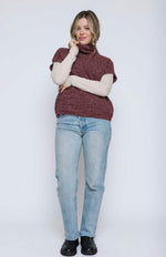 Load image into Gallery viewer, Woman wearing a wine coloured turtleneck sweater and light blue jeans on a white background