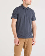 Load image into Gallery viewer, Man wearing a dark blue/grey polo shirt and beige pants on a light gray background