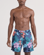 Load image into Gallery viewer, Man wearing a navy floral swim trunk on a light gray background