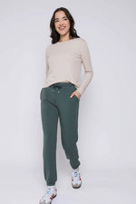 Load image into Gallery viewer, Woman wearing a beige sweater and green joggers on a white background