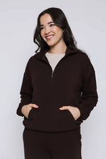 Load image into Gallery viewer, Woman wearing a brown 1/2 zip-up sweatshirt against a white background
