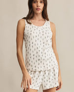 Load image into Gallery viewer, Woman wearing a white sleeveless tank and shorts with small floral patterns on a beige background