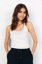 Load image into Gallery viewer, A woman wearing a white sleeveless tank top and black pants standing against a plain background.