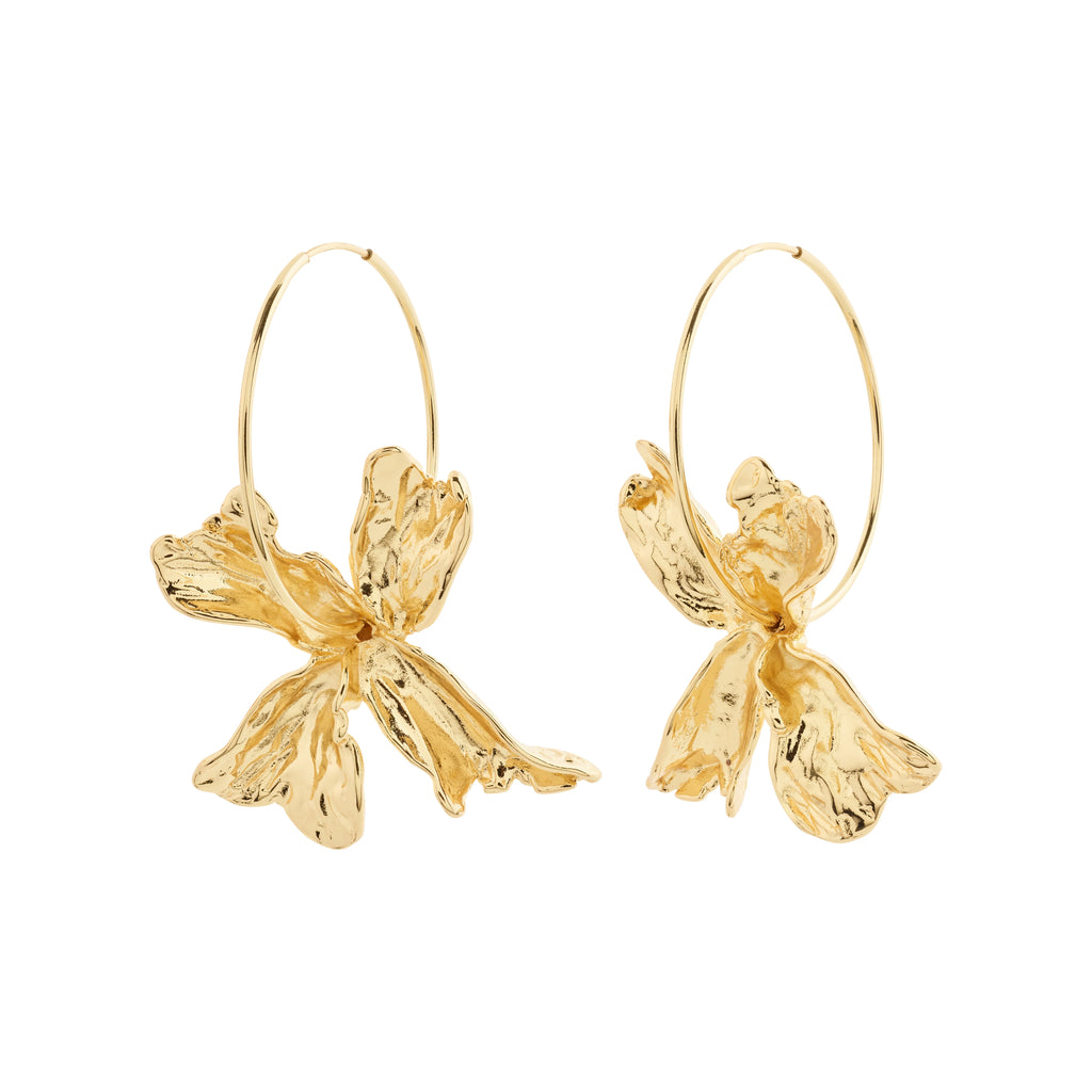 Sleek gold hoops with large flower pendants offer a distinct, opulent bohemian style. 