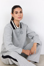 Load image into Gallery viewer, Woman wearing a gray sweatshirt with black and white polo collar.
