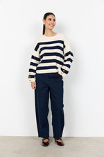 Load image into Gallery viewer, Woman wearing a navy and white striped sweater with gold button on the sleeves. 
