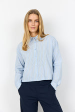 Load image into Gallery viewer, Woman wearing a light blue striped long sleeve shirt and dark pants against a white background
