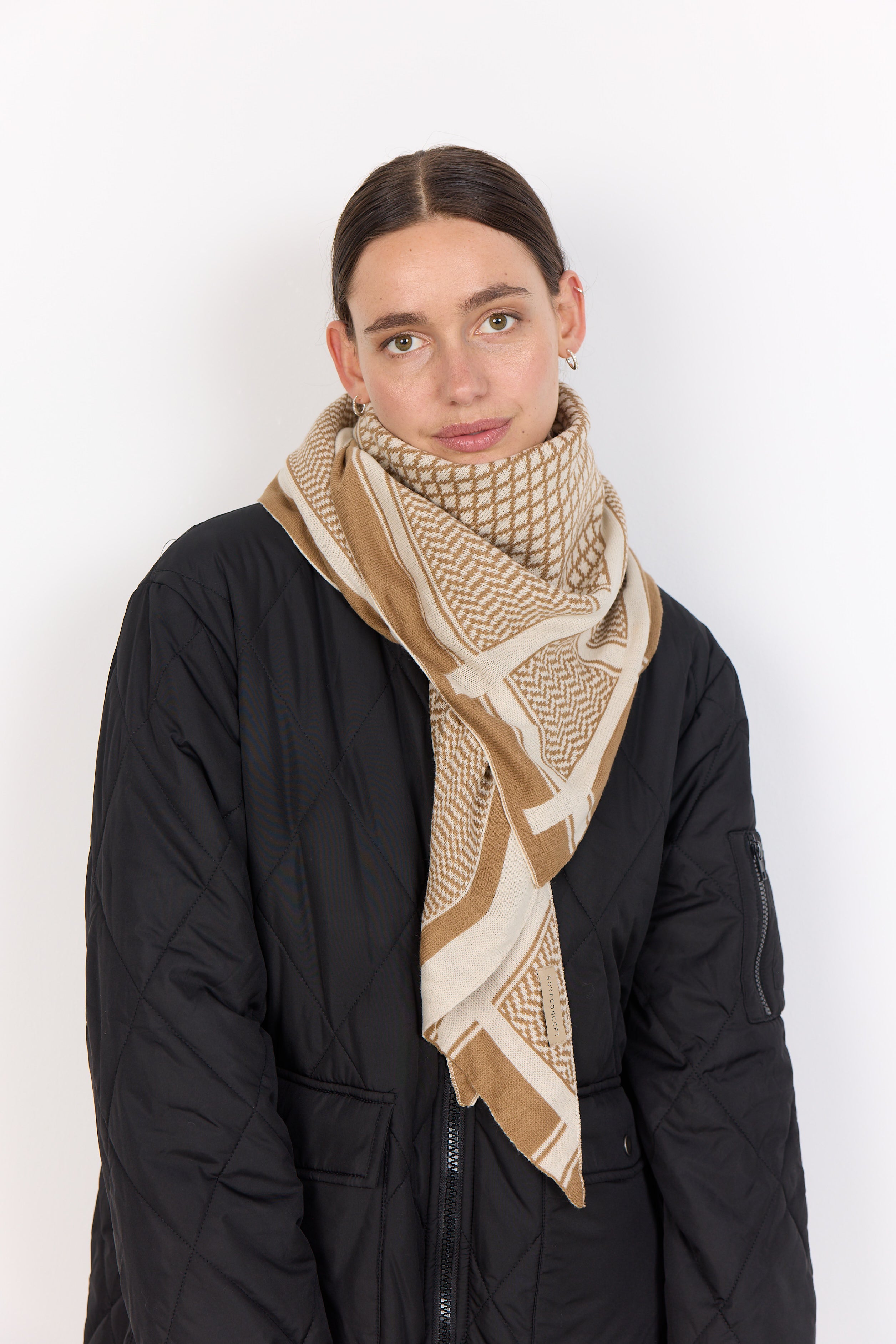 Person wearing a beige patterned scarf on a white background