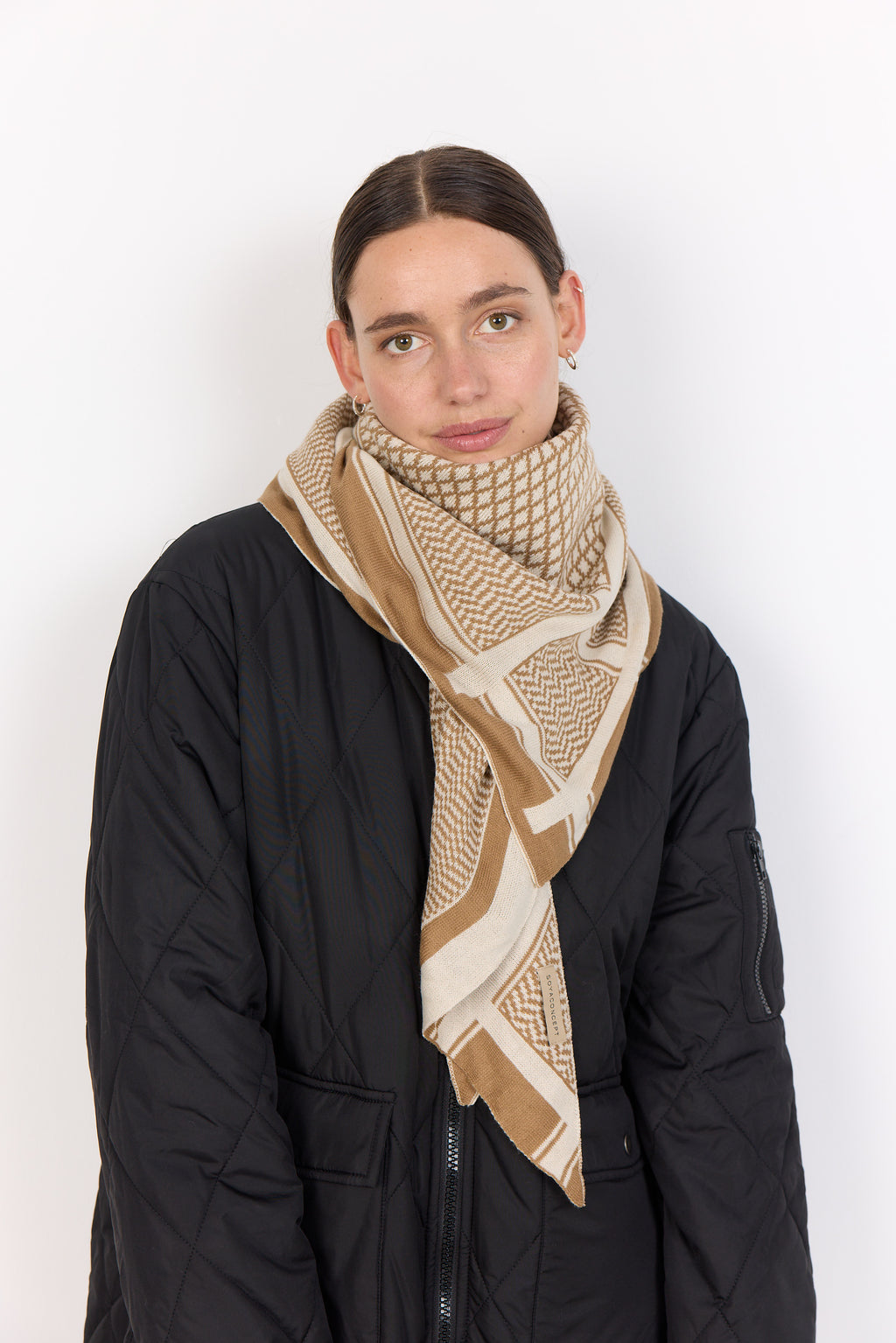 Person wearing a beige patterned scarf on a white background