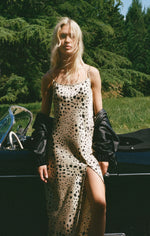 Load image into Gallery viewer, Woman in an animal print satin sheath dress standing next to a vintage car in a natural setting
