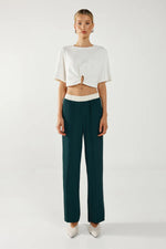 Load image into Gallery viewer, Woman wearing a white top and dark green pants on a white background

