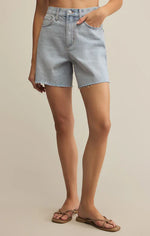 Load image into Gallery viewer, Person wearing light blue denim shorts on a beige background
