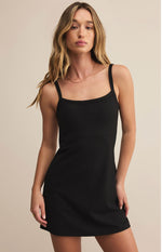Load image into Gallery viewer, Woman wearing a black slip dress  with built in shorts against a beige background

