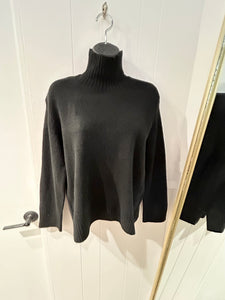 Black turtleneck sweater with rib detail on cuffs, bottom hem, and neck. 