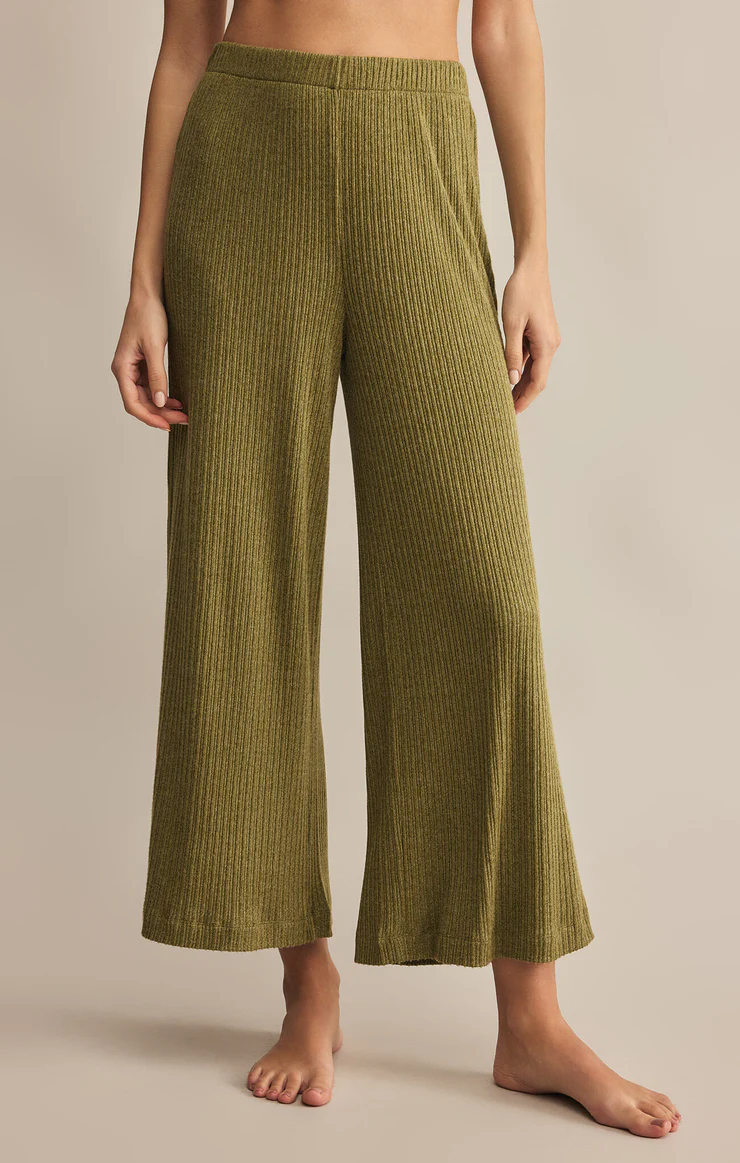 Green ribbed pants worn by a person on a beige background