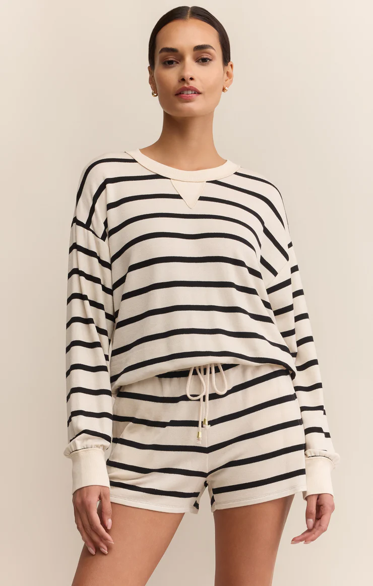 Woman wearing a black and white striped long-sleeve top and shorts on a beige background