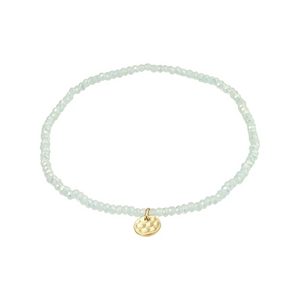 Aqua beaded bracelet with a gold charm on a white background