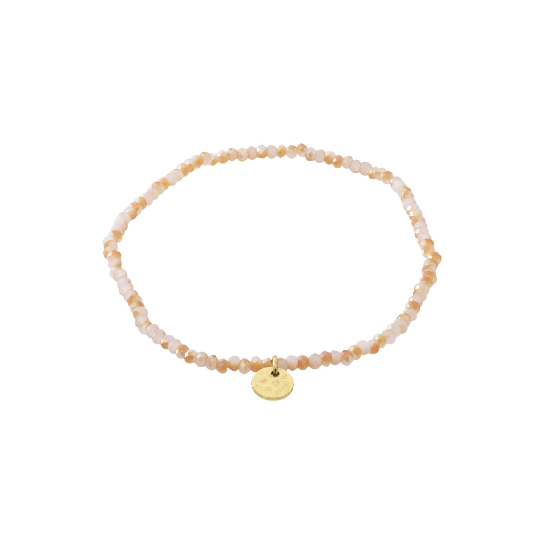 Beaded bracelet in shades of pink with a gold charm on a white background