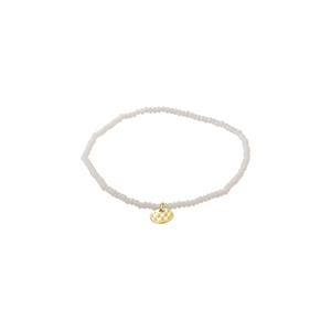 White beaded bracelet with a gold charm on a white background