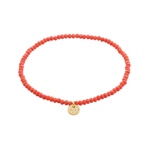 Peach beaded bracelet with a gold tag on a white background