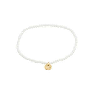 White beaded bracelet with a gold pendant on a white background