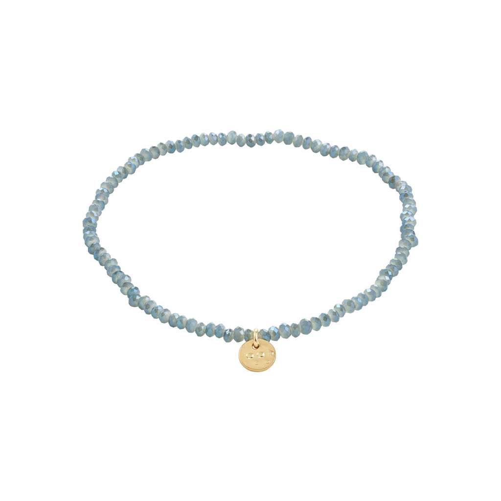Dusty blue beaded bracelet with a gold charm on a white background