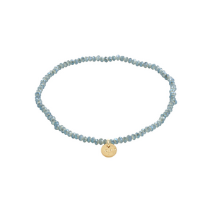 Dusty blue beaded bracelet with a gold charm on a white background