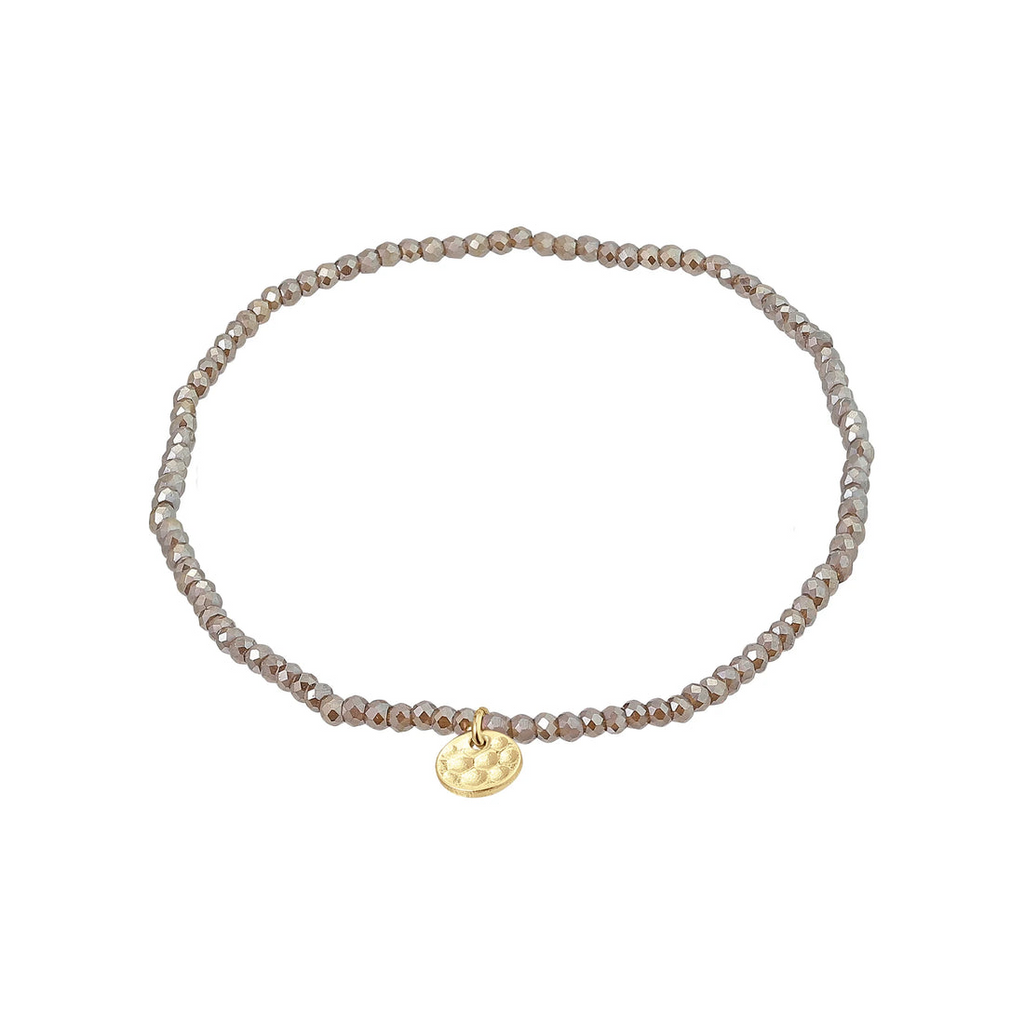 Delicate grey beaded bracelet with a gold charm on a white background