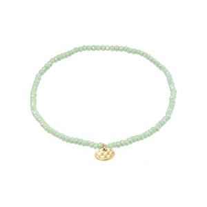 Lime green beaded bracelet with a gold charm on a white background