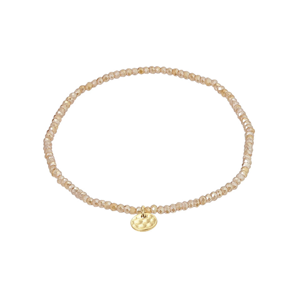 Beaded nude peach bracelet with a gold charm on a white background