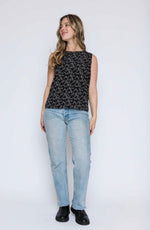 Load image into Gallery viewer, Woman wearing a black sleeveless top with white patterns and light blue jeans on a white background
