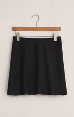 Load image into Gallery viewer, Black satin mini skirt on a wooden hanger against a white background
