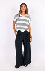 Load image into Gallery viewer, Woman wearing a black and white striped open knit shirt and wide-leg pants on a white background
