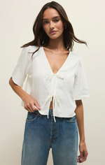 Load image into Gallery viewer, Woman wearing a white blouse with a tie front and blue jeans on a plain background

