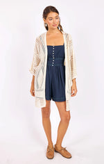 Load image into Gallery viewer, Woman wearing a navy romper with a beige pointelle cardigan on a white background
