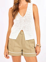 Load image into Gallery viewer, Woman wearing a white v-neck knitted sleeveless top and beige shorts on a plain background
