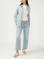 Load image into Gallery viewer, Person wearing a light blue denim shirt jacket with brown buttons and jeans on a white background
