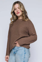 Load image into Gallery viewer, Woman wearing a brown textured  sweater and light blue jeans against a white background
