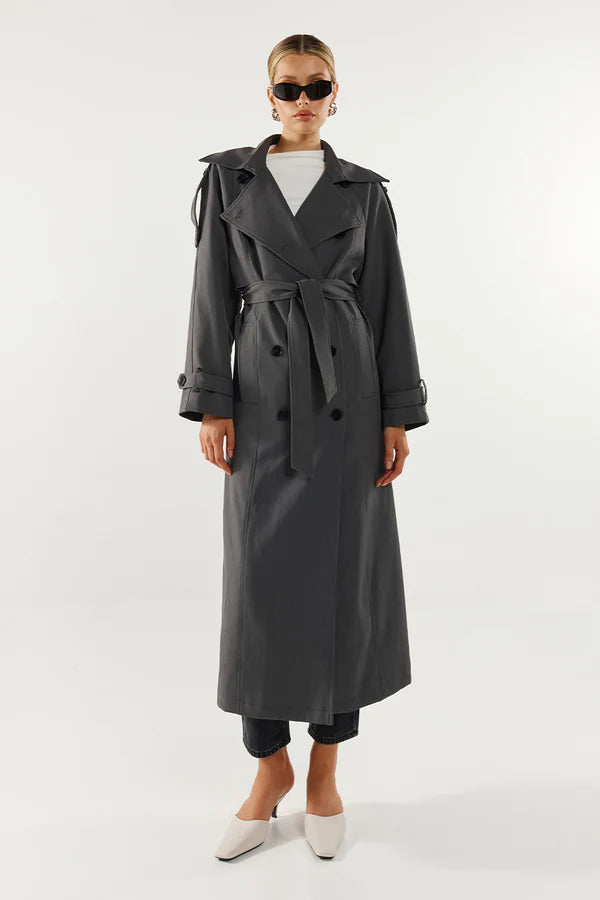 Person wearing a long gray trench coat on a white background