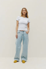 Load image into Gallery viewer, Woman wearing a light grey t-shirt and light blue jeans on a plain background
