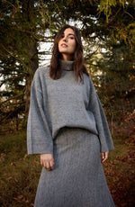 Load image into Gallery viewer, Grey pullover that features a ribbed turtleneck and long sleeves with a relaxed fit, offering a textured knit that adds depth. 
