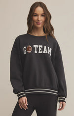 Load image into Gallery viewer, Woman wearing a black sweatshirt with &#39;GO TEAM&#39; text and a football graphic on a beige background
