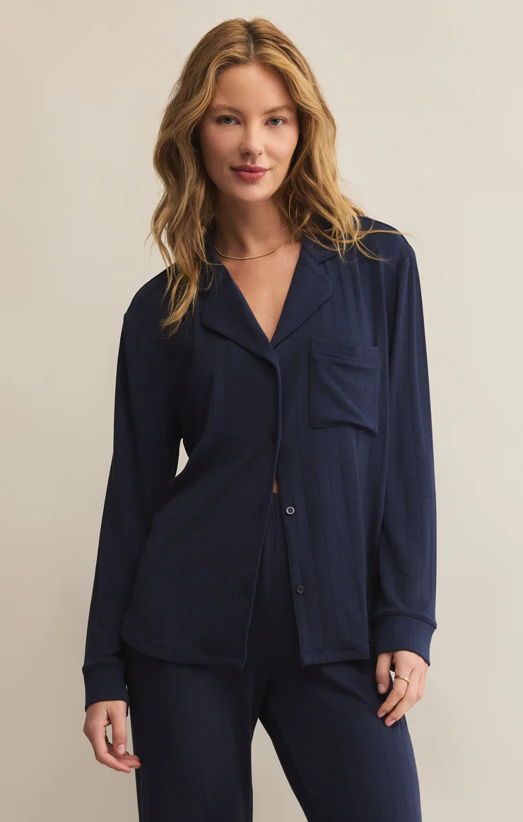 Woman wearing a navy blue pajama set against a beige background