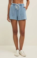 Load image into Gallery viewer, Person wearing light blue knit denim  shorts with a drawstring on a beige background
