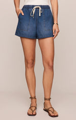 Load image into Gallery viewer, Person wearing blue denim shorts on a beige background
