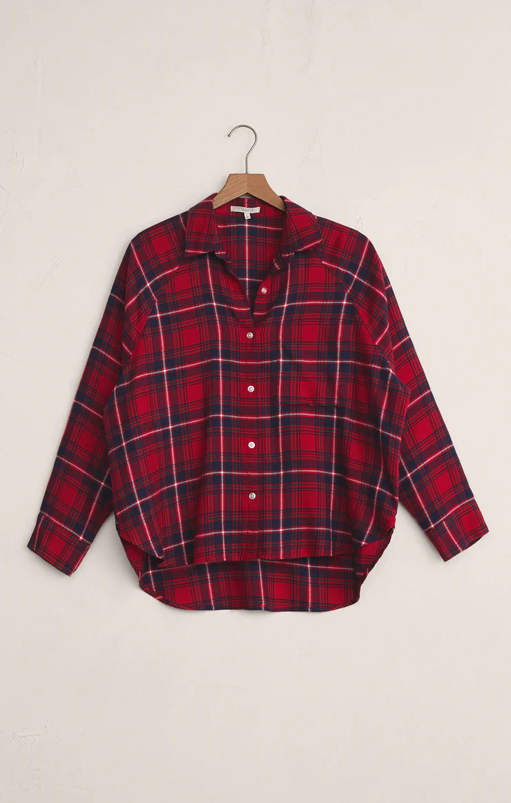 Red and black plaid shirt on a hanger against a beige background