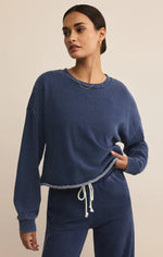Load image into Gallery viewer, Woman wearing a blue knit denim sweatshirt against a beige background
