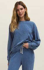 Load image into Gallery viewer, Woman wearing a blue knit denim crewneck sweatshirt and pants on a beige background
