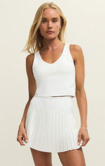 Load image into Gallery viewer, Woman wearing a white tank top and pleated skirt on a beige background
